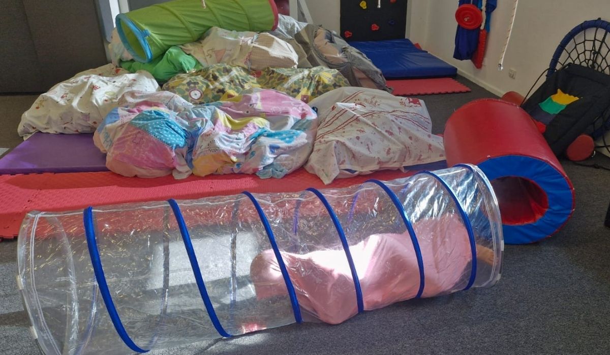 Therapy room set up with tunnels, mats and soft play equipment
