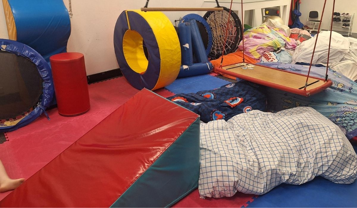 Clinic sensory gym with a trampoline, tunnels, platform swing and soft play equipment